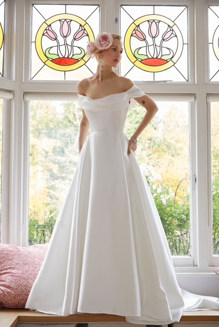 Rowan by Alan Hannah, British Designer. A pleated A-line wedding dress with a Bardot neckline. A modern classic and she has pockets.