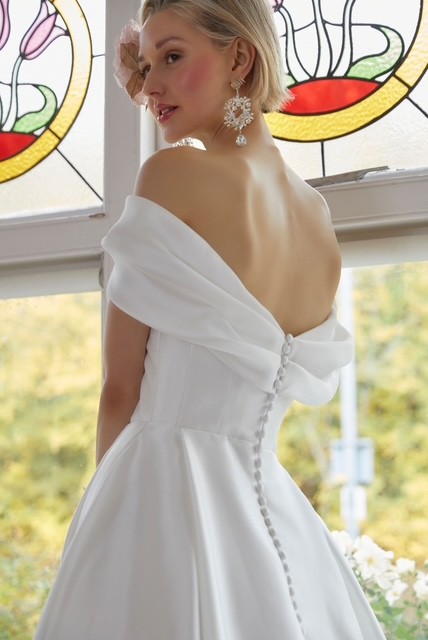 Rowan by Alan Hannah, British Designer. A pleated A-line wedding dress with a Bardot neckline. A modern classic and she has pockets.